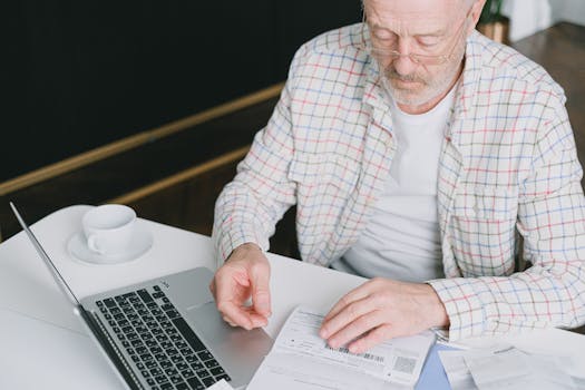 elderly man reviewing budget on a laptop